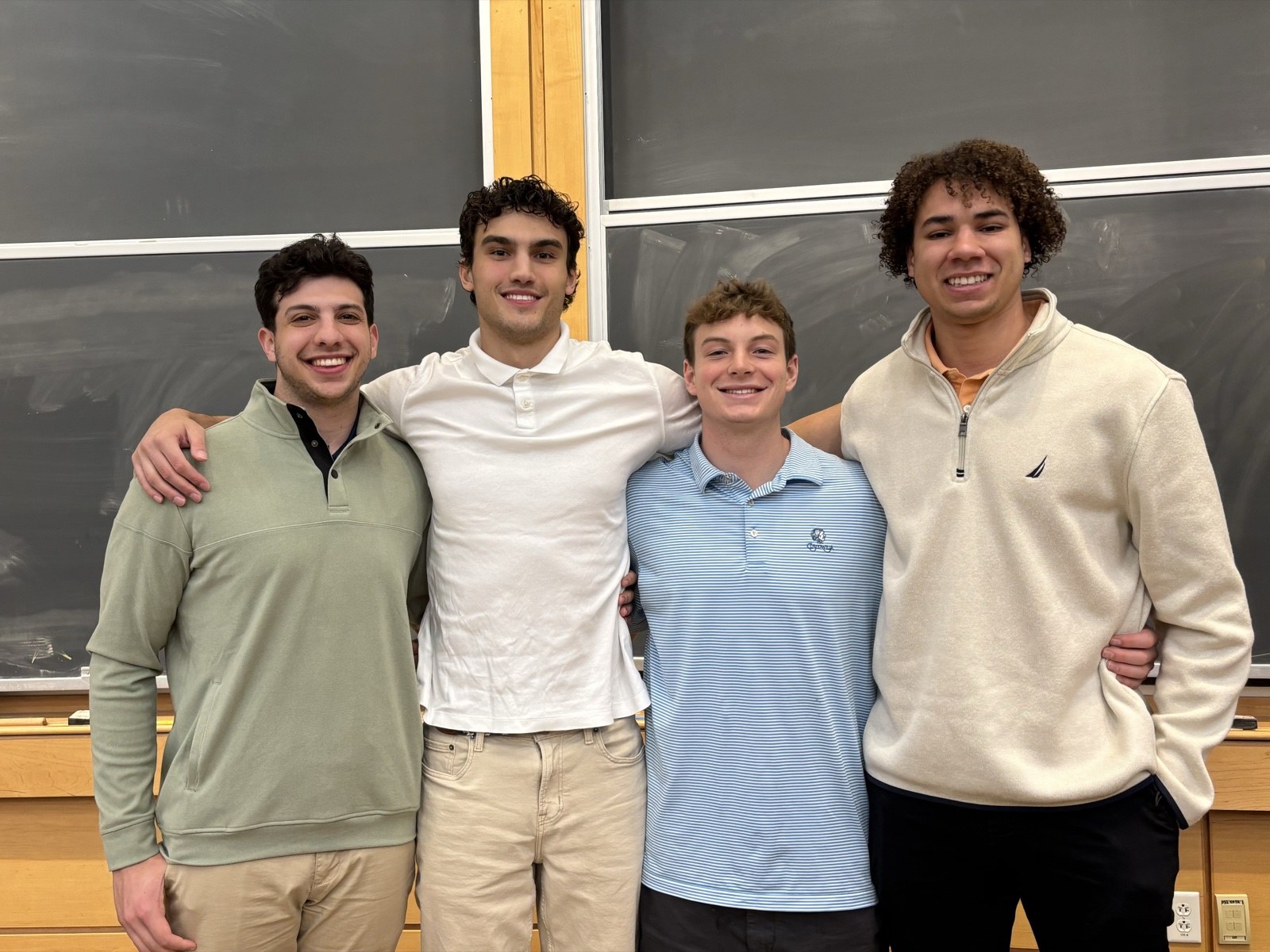 The four MoveOn founders standing together in a classroom after winning the hackathon